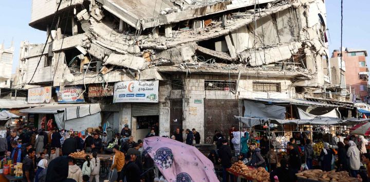 Palestinos compran alimentos debajo de un edificio destruido en el mercado Zawiya de la ciudad de Gaza por Ramadán. Foto de Omar AL-QATTAA / AFP