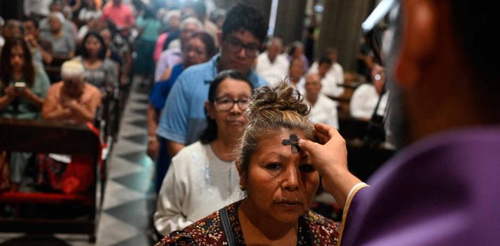 Una mujer recibe la señal de la cruz con ceniza en la frente de un sacerdote durante las celebraciones del Miércoles de Ceniza en la parroquia El Calvario en San Salvador. Foto de Marvin RECINOS / AFP