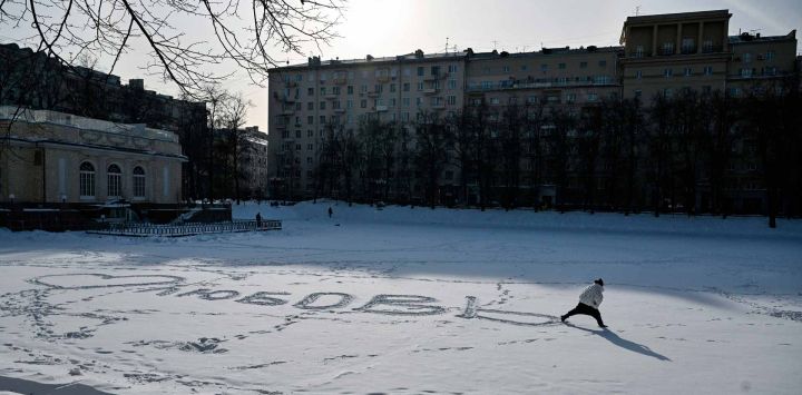 Una mujer escribe la palabra "Amor" en ruso sobre la manta de nieve de los helados Estanques del Patriarca en el centro de Moscú. Foto de Hector RETAMAL / AFP