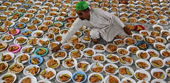 Un voluntario prepara los platos de comida de Iftar en el primer día del mes sagrado islámico de Ramadán en el santuario Data Darbar en Lahore. Foto de Arif ALI / AFP