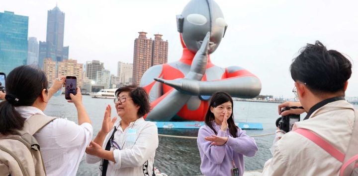 Turistas posan junto a un inflable gigante de Ultraman expuesto en Kaohsiung Wonderland. Foto de I-Hwa Cheng / AFP