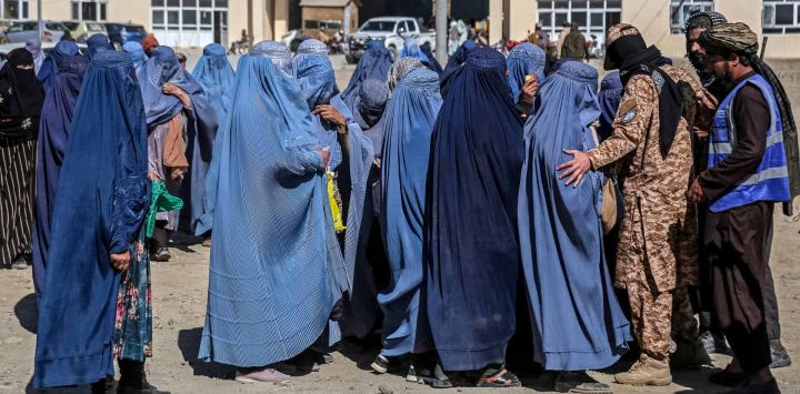 Mujeres afganas vestidas con burka hacen fila para recibir ayuda alimentaria de una organización benéfica local. Foto de Mohammad Faisal NAWEED / AFP