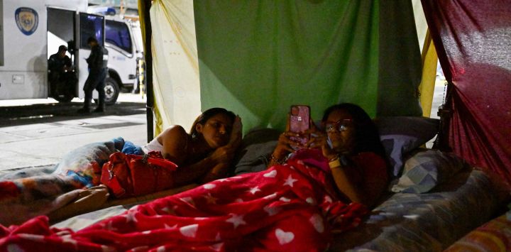 Parientes de presos políticos duermen en una carpa instalada frente a oficiales de la policía nacional bolivariana durante una protesta frente a la prisión de la Zona 7 de la Policía Nacional Bolivariana (PNB) en Caracas. Foto de Juan BARRETO / AFP