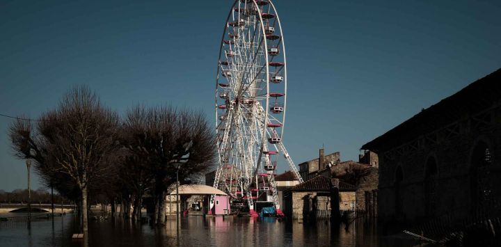 Una noria se encuentra parcialmente sumergida en aguas de inundación cerca de edificios históricos en Saintes, en el suroeste de Francia. Foto de Philippe LOPEZ / AFP