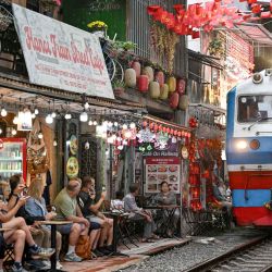 Los turistas toman fotos mientras un tren pasa por la vía del ferrocarril en la popular calle del tren en Hanoi. Foto de Nhac NGUYEN / AFP | Foto:AFP