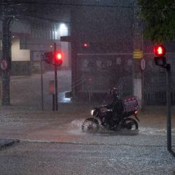 Un repartidor conduce una motocicleta en una calle inundada durante fuertes lluvias en Juiz de Fora, estado de Minas Gerais, Brasil. Foto de Pablo PORCIUNCULA / AFP | Foto:AFP