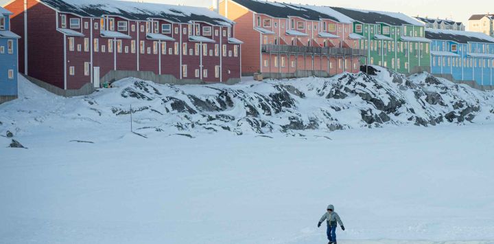 Un niño patina sobre hielo en un lago congelado junto a viviendas recientemente construidas en Nuuk, Groenlandia. Foto de Florent VERGNES / AFP