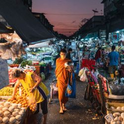 Un monje camina junto a los puestos de vendedores de productos frescos mientras recoge limosnas en el Mercado Khlong Toei en Bangkok. Foto de ANTHONY WALLACE / AFP | Foto:AFP