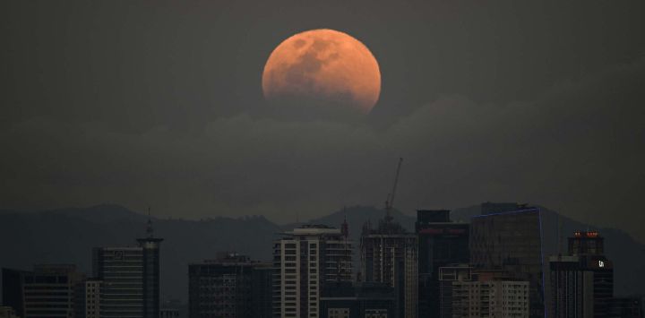 Una luna llena, también conocida como la "Luna de Sangre", se eleva sobre los edificios en Manila. Foto de Ted ALJIBE / AFP