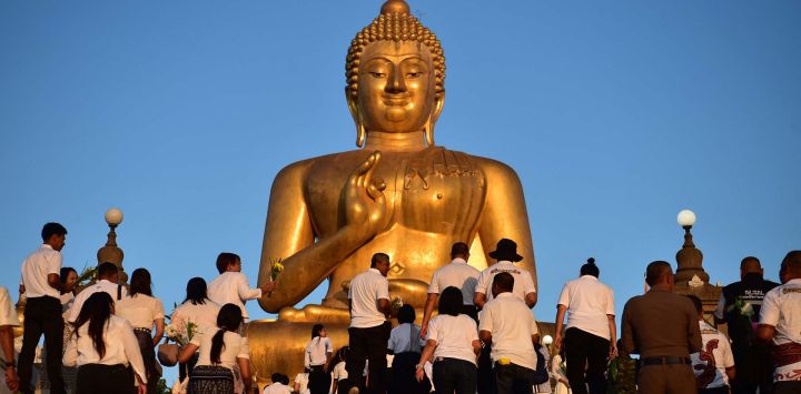 Devotos budistas caminan hacia una estatua gigante de Buda durante un evento para conmemorar el Día de Makha Bucha. Foto de Madaree TOHLALA / AFP