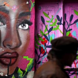 Un hombre camina junto a un grafiti en la pared de una casa en un callejón del barrio La Candelaria en Bogotá. Foto de Pablo VERA / AFP | Foto:AFP