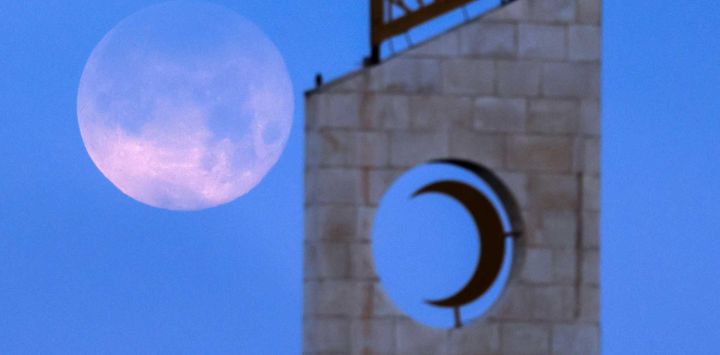 La luna llena, también conocida como la "Luna de Sangre", se alza tras el minarete de una mezquita en la ciudad de Ramala, en la Cisjordania. Foto de Zain JAAFAR / AFP