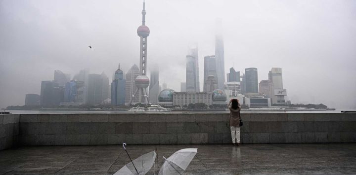 Una mujer toma una foto del distrito financiero de Lujiazui al otro lado del río Huangpu desde el paseo del Bund en Shanghái. Foto de Jade GAO / AFP