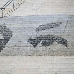 Un hombre cubriéndose del sol con un paraguas descansa en un mosaico que muestra los ojos del fallecido presidente venezolano Hugo Chávez. Foto de Juan BARRETO / AFP | Foto:AFP