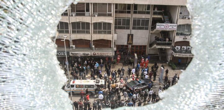 Una ventana rota da vista a los socorristas que trabajan cerca de un edificio que fue atacado por un bombardeo israelí en la ciudad costera del sur del Líbano, Sidón. Foto de MAHMOUD ZAYYAT / AFP