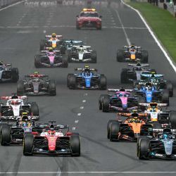 El piloto monegasco de Ferrari, Charles Leclerc (centro, izq.) y el piloto británico de Mercedes, George Russell (segundo delantero, der.) conducen al frente del grupo durante el inicio del Gran Premio de Australia de Fórmula Uno en el Circuito Albert Park en Melbourne. | Foto:Paul Crock / AFP