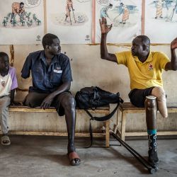 Pacientes con pérdida de extremidades conversan sentados tras ser atendidos por especialistas en un centro de rehabilitación apoyado por el Comité Internacional de la Cruz Roja (CICR) en Yuba. La escasa atención médica disponible en Sudán del Sur se proporciona casi en su totalidad a través de donantes extranjeros, y más del 80 % está cubierta por ONG. Mientras el país de África Oriental se hunde de nuevo en la guerra civil, un informe reciente de las Naciones Unidas documentó cómo los líderes del país han malgastado y robado miles de millones de dólares en ingresos petroleros. | Foto:LUIS TATO / AFP