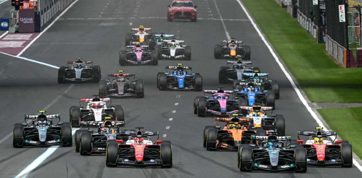 El piloto monegasco de Ferrari, Charles Leclerc (centro, izq.) y el piloto británico de Mercedes, George Russell (segundo delantero, der.) conducen al frente del grupo durante el inicio del Gran Premio de Australia de Fórmula Uno en el Circuito Albert Park en Melbourne.