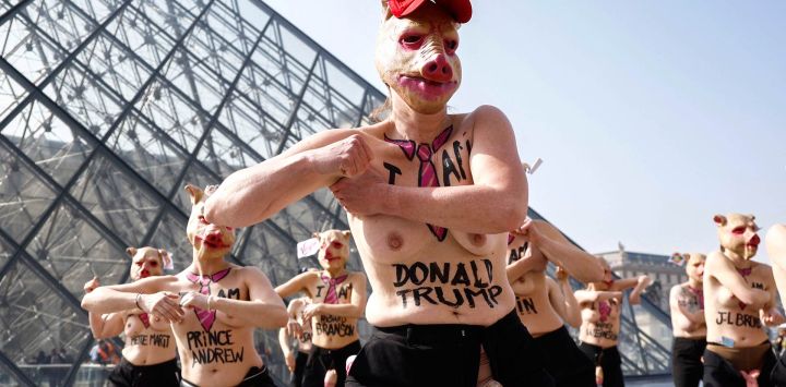 Miembros en topless del grupo activista feminista FEMEN con máscaras de cerdo participan en una protesta en el Museo del Louvre junto a la Pirámide del Louvre, diseñada por el arquitecto chino-estadounidense Ieoh Ming Pei.
