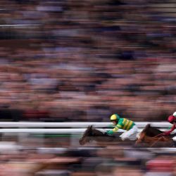 El jockey Richie McLernon monta al caballo de carreras n.° 7 Johnnywho (izq.) para ganar por delante del segundo clasificado Jagwar (der.), montado por Mark Walsh, y del tercer clasificado Quebecois, montado por Harry Cobden, en el Trustmarque Ultima Handicap Chase, el primer día del Festival de Cheltenham en el hipódromo de Cheltenham, en Cheltenham, oeste de Inglaterra. | Foto:Adrian Dennis / AFP