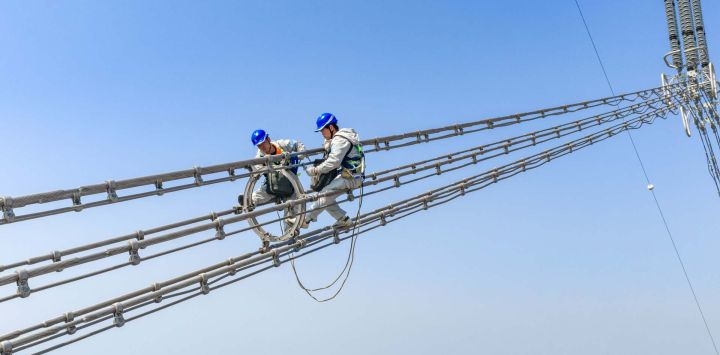 Vista aérea tomada con un dron de trabajadores de mantenimiento revisando la Línea Jintang de ultra alta tensión de ±800 kV junto al río Yangtse, en el distrito de Zongyang de la ciudad de Tongling, en la provincia de Anhui, en el este de China.
