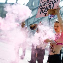 Miembros en topless del grupo activista feminista FEMEN se quitan las máscaras de cerdo y encienden bengalas rosas durante una acción en el Museo del Louvre junto a la Pirámide del Louvre, diseñada por el arquitecto chino-estadounidense Ieoh Ming Pei. | Foto:KENZO TRIBOUILLARD / AFP