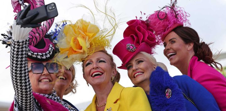 Los aficionados a las carreras posan para fotografías a su llegada al hipódromo de Cheltenham, en el oeste de Inglaterra, durante el segundo día del Festival de Cheltenham.