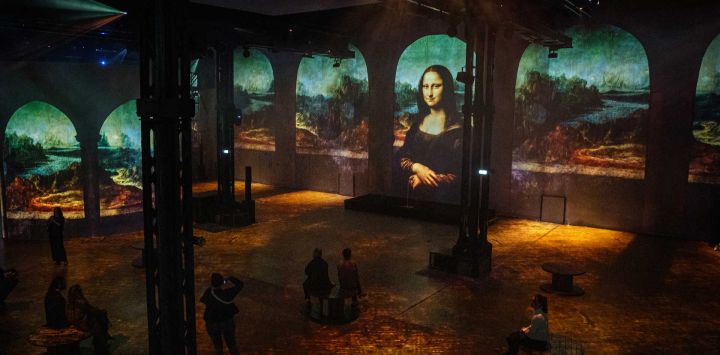Los visitantes observan una instalación de luz que presenta la obra maestra que representa a Lisa del Giocondo, "La Mona Lisa" (1503-1519), del pintor, dibujante, ingeniero, científico, teórico, escultor y arquitecto renacentista italiano Leonardo Da Vinci (1452-1519), en el Atelier des Lumières durante una vista previa para la prensa de la exposición inmersiva titulada "Renacimiento: De da Vinci, Rafael y Miguel Ángel" en vísperas de su inauguración en París.