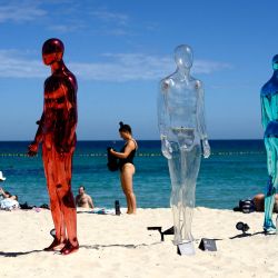Esta foto muestra a un bañista frente a la instalación "ART (Tiempo Real Artificial)" de Erica Zaino, en la exposición Esculturas junto al Mar en la playa de Cottesloe, Perth, Australia. | Foto:ANTONY DICKSON / AFP