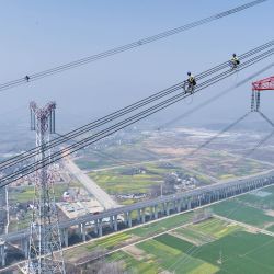 Vista aérea tomada con un dron de trabajadores de mantenimiento revisando la Línea Jintang de ultra alta tensión de ±800 kV junto al río Yangtse, en el distrito de Zongyang de la ciudad de Tongling, en la provincia de Anhui, en el este de China. | Foto:Xinhua/Zhou Mu