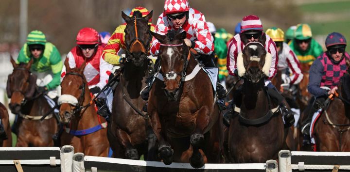 El jinete James Bowen, montado en Jingko Blue (centro), salta una valla para liderar y ganar la BetMGM Cup Handicap Hurdle en el Festival de Cheltenham, en el hipódromo de Cheltenham, en Cheltenham, oeste de Inglaterra.