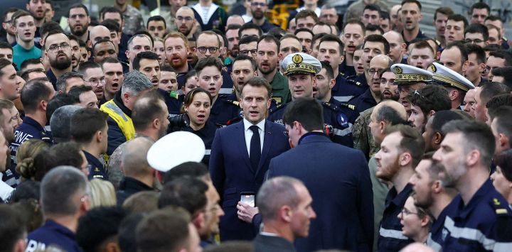 El presidente francés, Emmanuel Macron (centro), canta el himno nacional francés tras dirigirse a la tripulación del portaaviones Charles de Gaulle, desplegada en el mar Mediterráneo tras los ataques con drones iraníes contra Chipre, en el marco de su viaje a Chipre para abordar la seguridad regional.