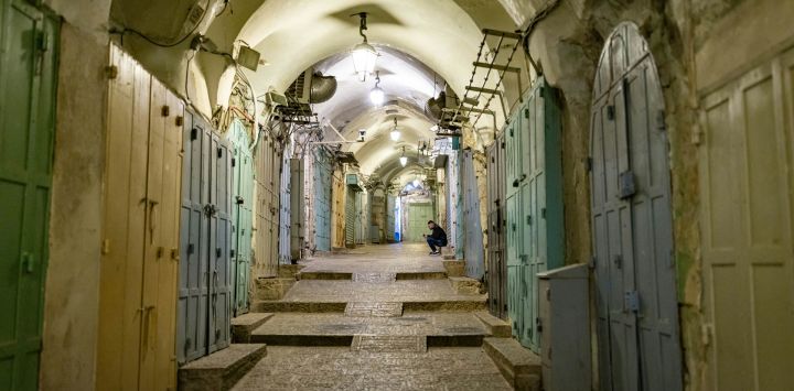 Un hombre se sienta frente a una tienda cerrada en la vacía Ciudad Vieja de Jerusalén. Una semana después del inicio de la ofensiva israelí-estadounidense contra Irán, millones de israelíes se ven interrumpidos día y noche por repetidas sirenas que les advierten que se dirijan a refugios ante la llegada de misiles iraníes.