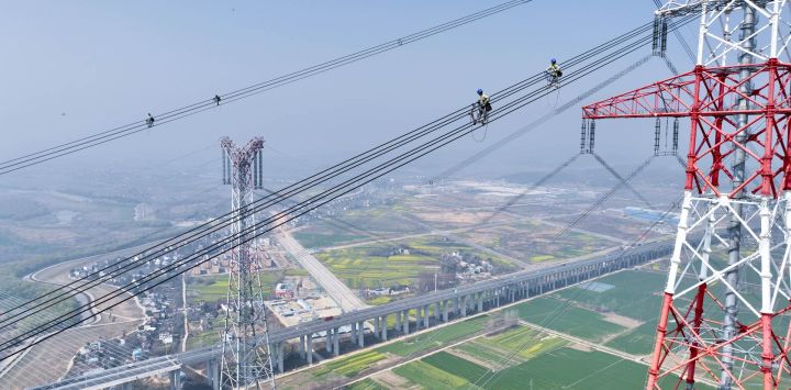 Vista aérea tomada con un dron de trabajadores de mantenimiento revisando la Línea Jintang de ultra alta tensión de ±800 kV junto al río Yangtse, en el distrito de Zongyang de la ciudad de Tongling, en la provincia de Anhui, en el este de China.