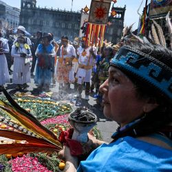Una mujer indígena observa mientras participa en una ceremonia para celebrar el inicio del año azteca —conocido como "Xiuhpohualli"— que marca el comienzo del ciclo agrícola y solar, en la Ciudad de México. | Foto:YURI CORTEZ / AFP