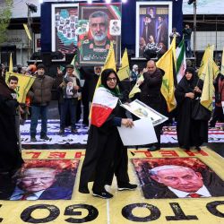 Una mujer iraní camina sobre carteles con imágenes del presidente estadounidense Donald Trump (izquierda) y del primer ministro israelí Benjamin Netanyahu mientras participa en la manifestación del Día de Al-Quds (Jerusalén), una conmemoración en apoyo al pueblo palestino durante el mes sagrado islámico del Ramadán, en Teherán. | Foto:AFP