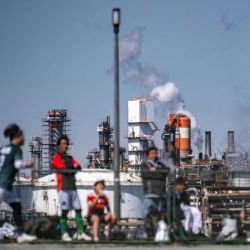 Varias personas juegan al fútbol en el parque Higashi-Ogishima Higashi, mientras se observan tanques de almacenamiento de energía cerca de una refinería de petróleo en la Zona Industrial de Keihin, un importante cinturón industrial de la bahía de Tokio, en la ciudad de Kawasaki, Japón. | Foto:Philip Fong / AFP