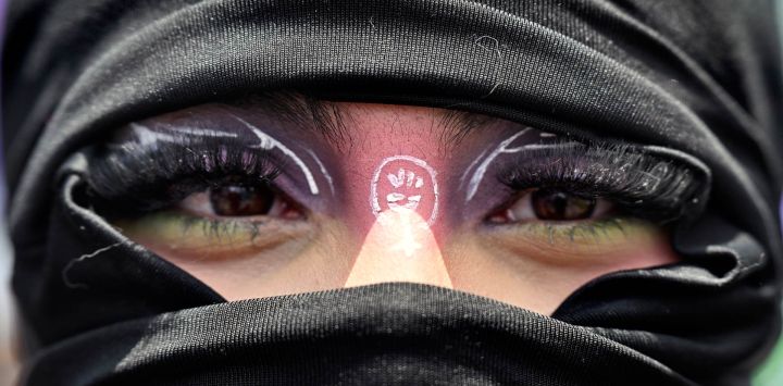Una mujer enmascarada participa en una marcha para conmemorar el Día Internacional de la Mujer en Bogotá, Colombia.