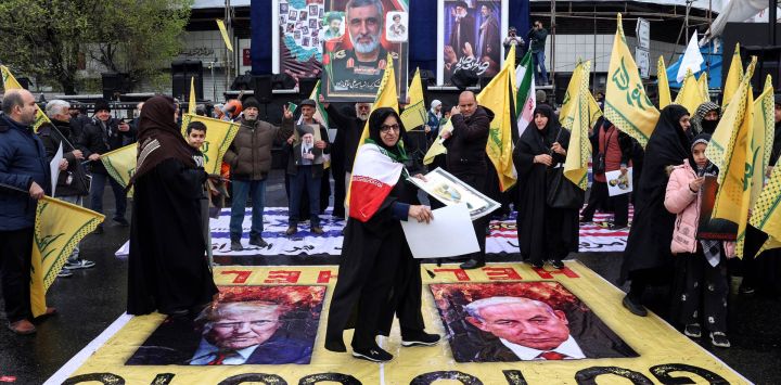 Una mujer iraní camina sobre carteles con imágenes del presidente estadounidense Donald Trump (izquierda) y del primer ministro israelí Benjamin Netanyahu mientras participa en la manifestación del Día de Al-Quds (Jerusalén), una conmemoración en apoyo al pueblo palestino durante el mes sagrado islámico del Ramadán, en Teherán.