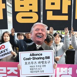 Un manifestante surcoreano lleva una máscara del presidente estadounidense Donald Trump frente a pancartas con el lema "Oposición al despliegue de tropas" durante una protesta contra la solicitud de Trump de enviar buques de guerra al estrecho de Ormuz, frente a la embajada de Estados Unidos en Seúl, Corea del Sur. | Foto:Jung Yeon-je / AFP