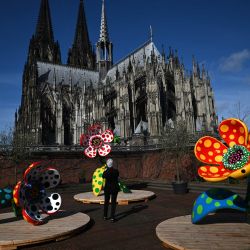 Un visitante toma una foto de la instalación "Flores que hablan de mi corazón entregado al cielo" con la catedral de Colonia de fondo durante la presentación previa de una exposición de la artista japonesa Yayoi Kusama en el Museo Ludwig de Colonia. | Foto:INA FASSBENDER / AFP