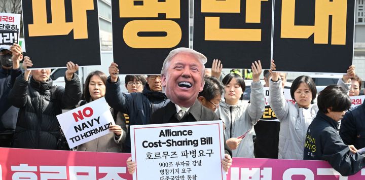 Un manifestante surcoreano lleva una máscara del presidente estadounidense Donald Trump frente a pancartas con el lema "Oposición al despliegue de tropas" durante una protesta contra la solicitud de Trump de enviar buques de guerra al estrecho de Ormuz, frente a la embajada de Estados Unidos en Seúl, Corea del Sur.