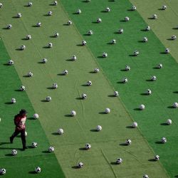 Un empleado del gobierno local camina entre pelotas antes del inicio de una clínica de fútbol de primer nivel en la plaza del Zócalo de la Ciudad de México, con el objetivo de establecer un nuevo récord mundial Guinness. | Foto:ALFREDO ESTRELLA / AFP
