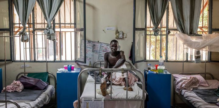 Mading Akol, recibe tratamiento en su cama de hospital por heridas de bala en la pierna en una sala del Hospital Militar de Juba, atendida por el Comité Internacional de la Cruz Roja (CICR). La escasa atención médica existente en Sudán del Sur depende casi en su totalidad de donantes extranjeros, y más del 80% está cubierta por ONG. Mientras el país de África Oriental se sumerge nuevamente en la guerra civil, un informe reciente de las Naciones Unidas documentó cómo los líderes del país han despilfarrado y robado miles de millones de dólares en ingresos petroleros. En consecuencia, ONG como el Comité Internacional de la Cruz Roja (CICR) y Médicos Sin Fronteras (MSF) tienen que paliar las carencias. 