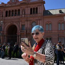 Un turista se toma una selfie mientras agentes de la Policía Federal custodian la Casa Rosada, palacio presidencial de Buenos Aires, tras una protesta contra el gobierno que exigía asistencia para personas con discapacidad. | Foto:LUIS ROBAYO / AFP