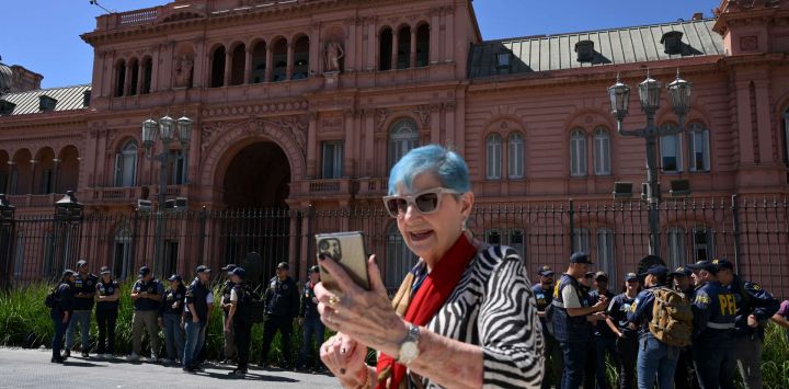 Un turista se toma una selfie mientras agentes de la Policía Federal custodian la Casa Rosada, palacio presidencial de Buenos Aires, tras una protesta contra el gobierno que exigía asistencia para personas con discapacidad.