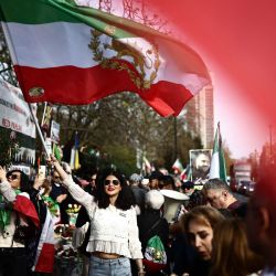 Un manifestante contra el régimen iraní ondea una bandera iraní anterior a la revolución de 1979 con el emblema del león y el sol durante una protesta frente a la embajada iraní en el centro de Londres, Inglaterra. | Foto:HENRY NICHOLLS / AFP