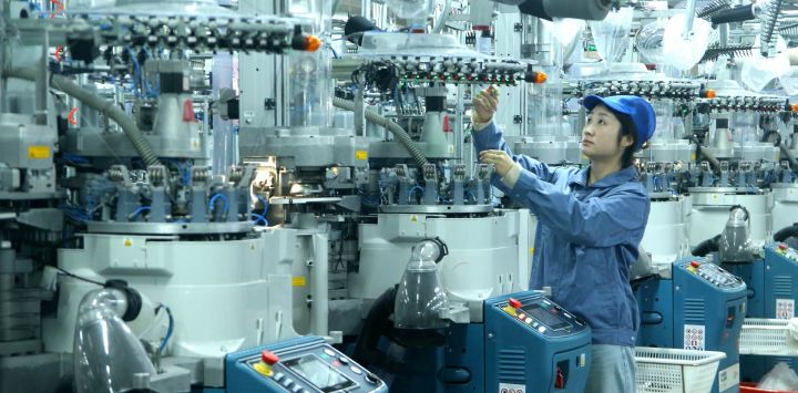 Un trabajador labora en la línea de producción de una empresa de calcetines, en el distrito de Qingdao, en la provincia de Shandong, en el este de China.