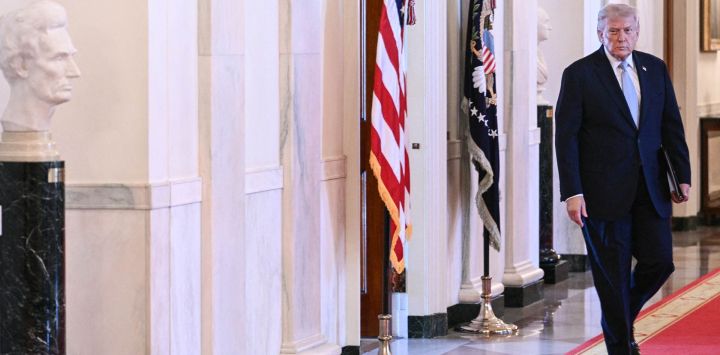 El presidente estadounidense Donald Trump camina por el Salón de la Cruz a su llegada a la ceremonia de entrega del Trofeo del Comandante en Jefe al equipo de fútbol americano Navy Midshipmen de la Academia Naval de los Estados Unidos en el Salón Este de la Casa Blanca en Washington, D.C.