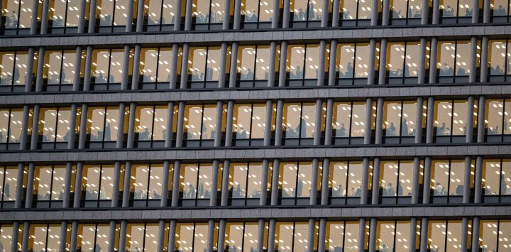 Empleados de una empresa aparecen sentados en sus escritorios en un edificio de oficinas en el distrito de Chiyoda, en el centro de Tokio.